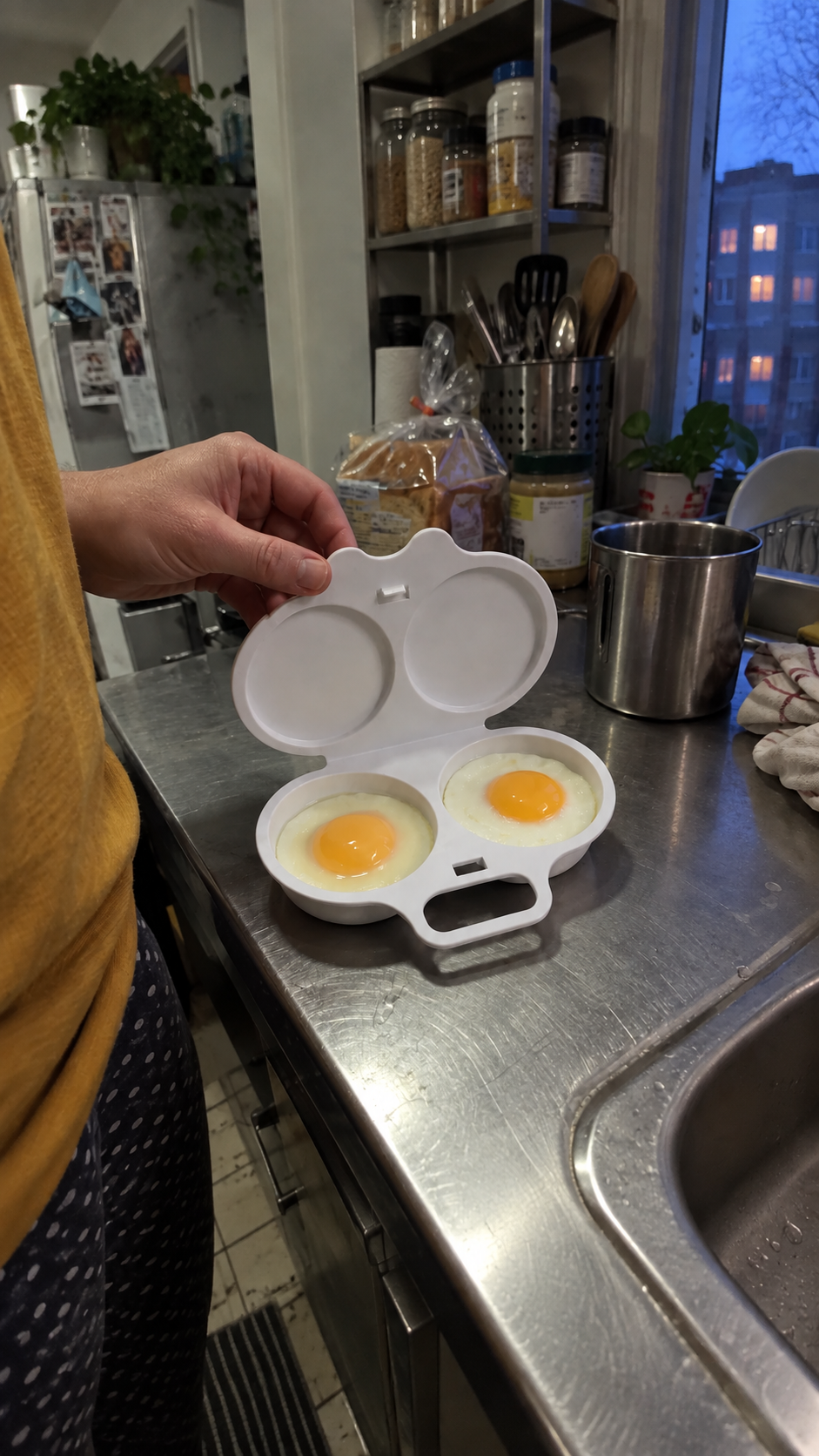 Illustrative scene: a person opening the white maker on a stainless-steel kitchenette counter at dusk