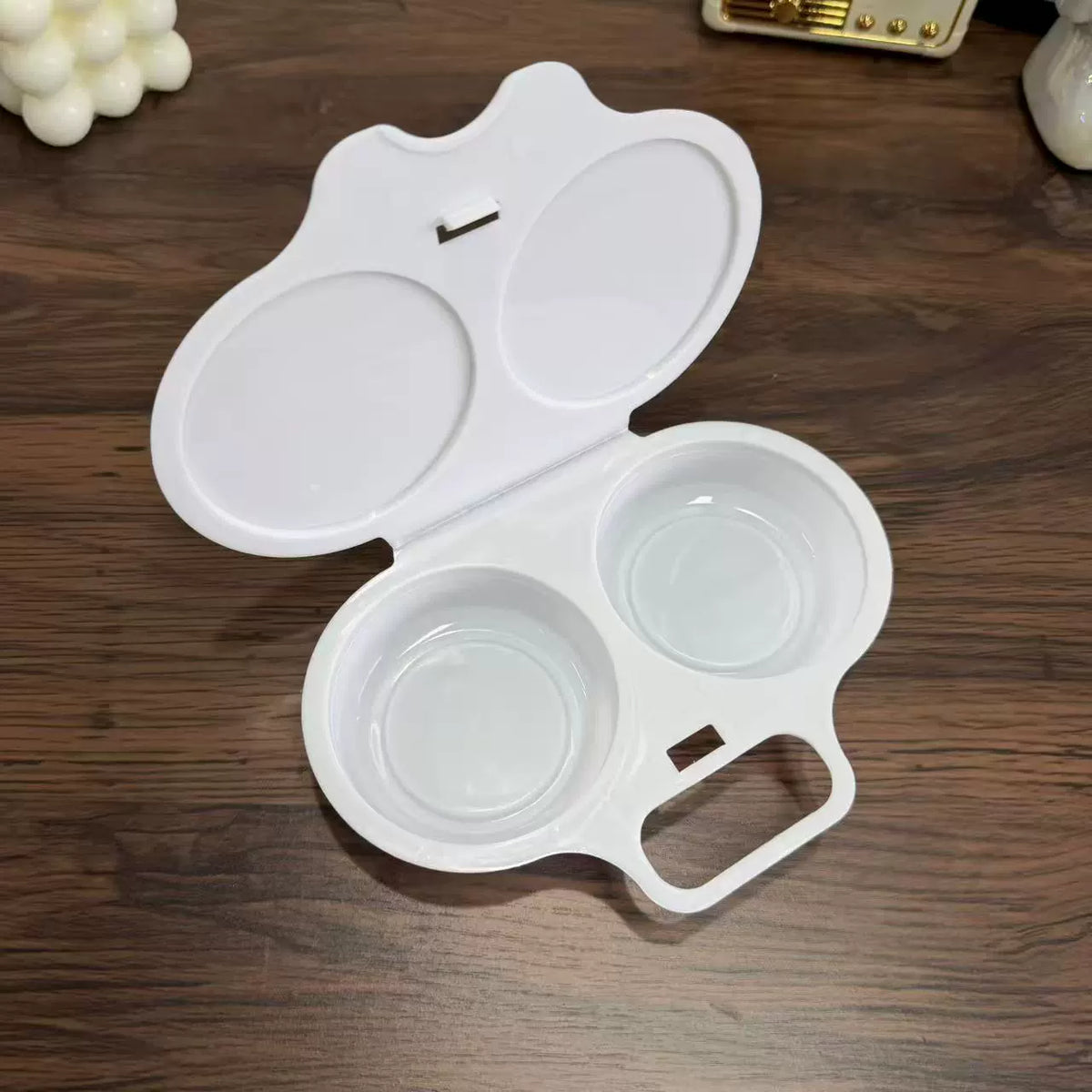 Open white maker showing its two round egg wells